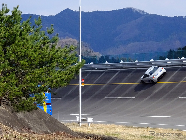 高速周回路バスツアーの横を220km/h超えで突っ走る、スバルドライビングアカデミートレーニング車（3月27日、栃木県佐野市・スバル研究実験センター）