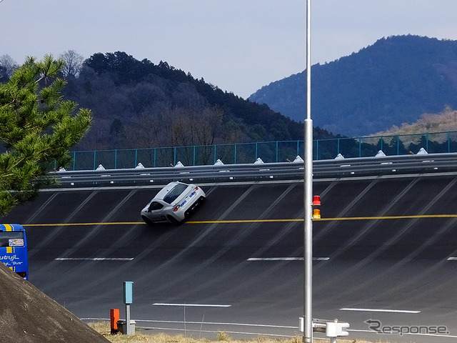 高速周回路バスツアーの横を220km/h超えで突っ走る、スバルドライビングアカデミートレーニング車（3月27日、栃木県佐野市・スバル研究実験センター）