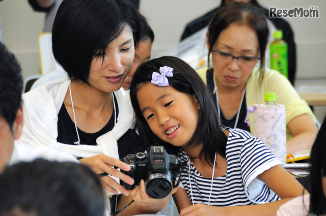 夏休みイベントの醍醐味は、親子で出来事を共有しながら学べること。子ども新聞に利用する写真を一緒に選定する親子のようす　＜撮影：稲葉九＞